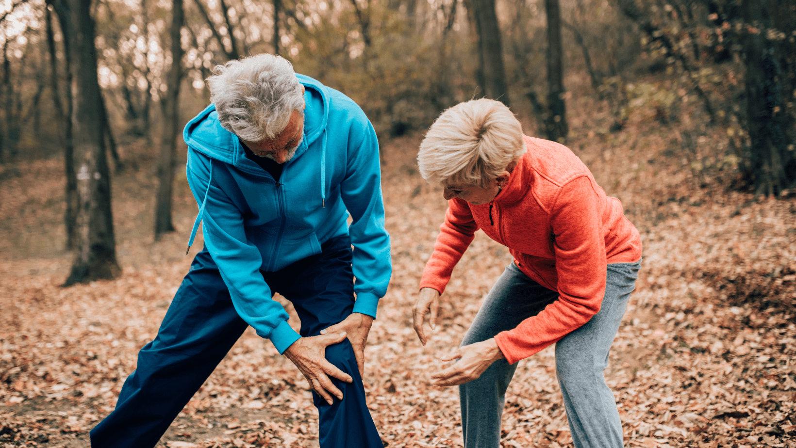 Man jogging in the woods holding injured knee while wife assists