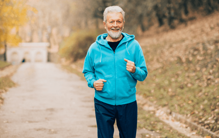 A middle aged man with gray hair and beard jogging in blue jacket