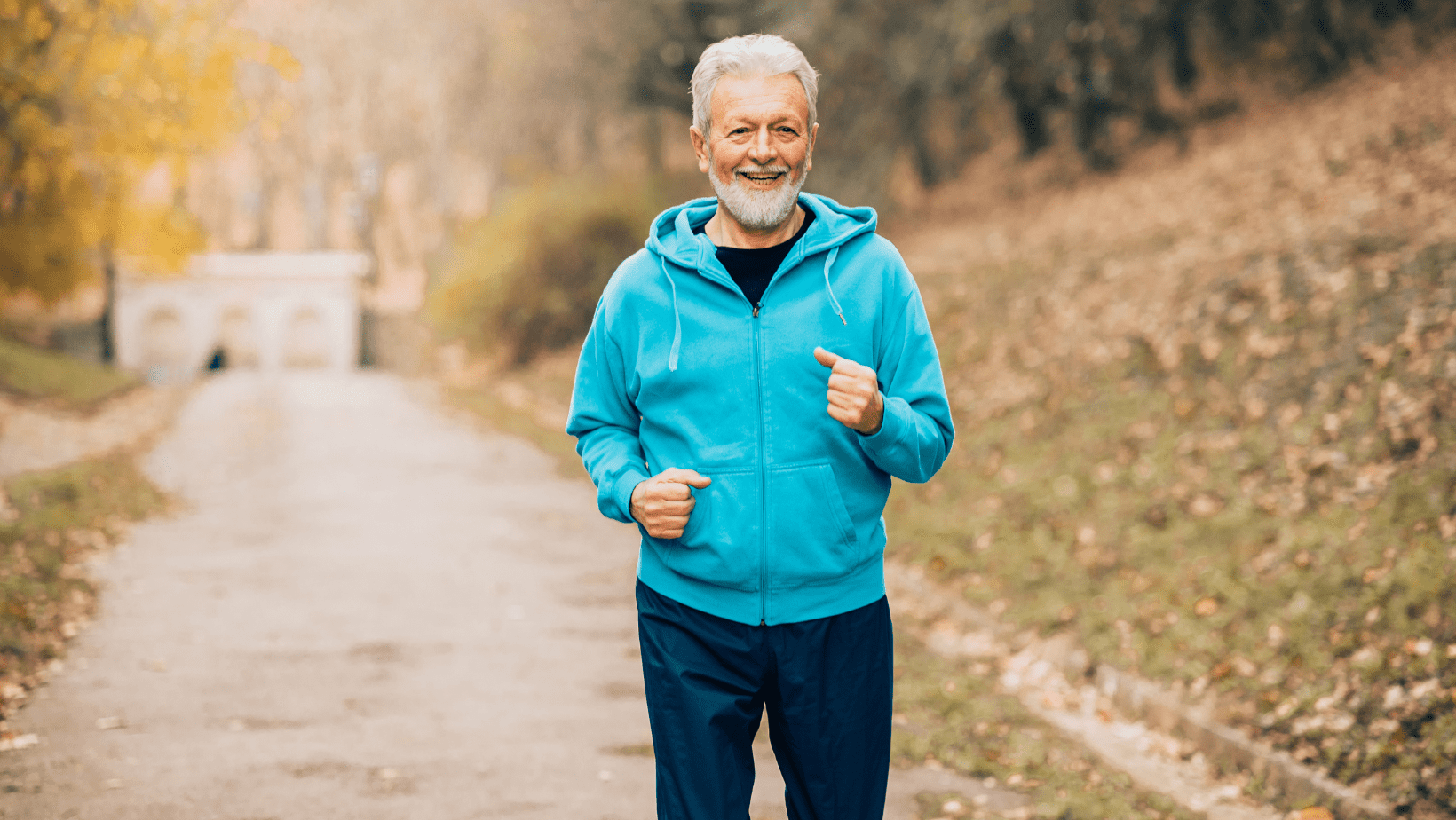 A middle aged man with gray hair and beard jogging in blue jacket