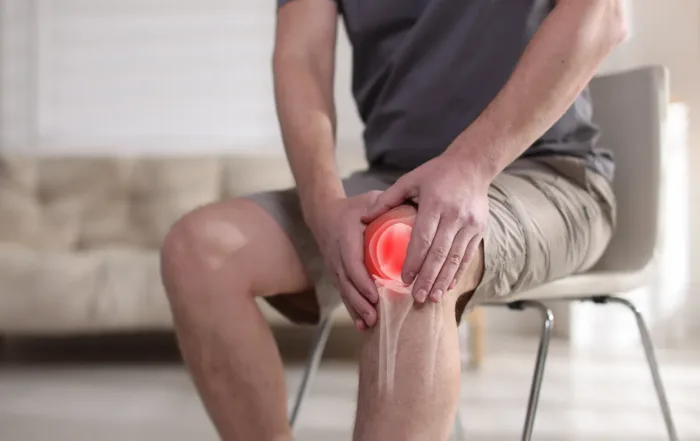 man holding his knee sitting on a chair