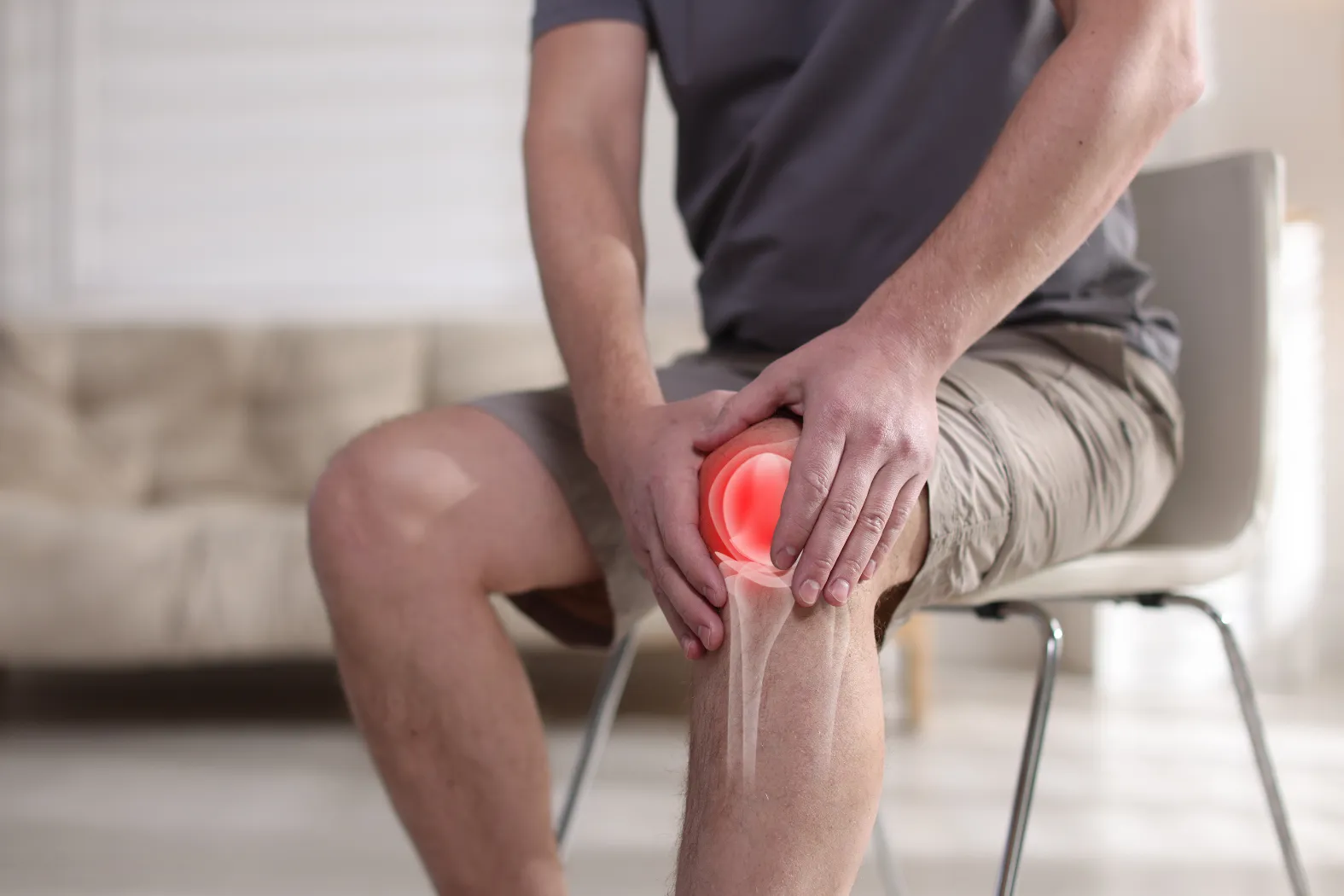 man holding his knee sitting on a chair